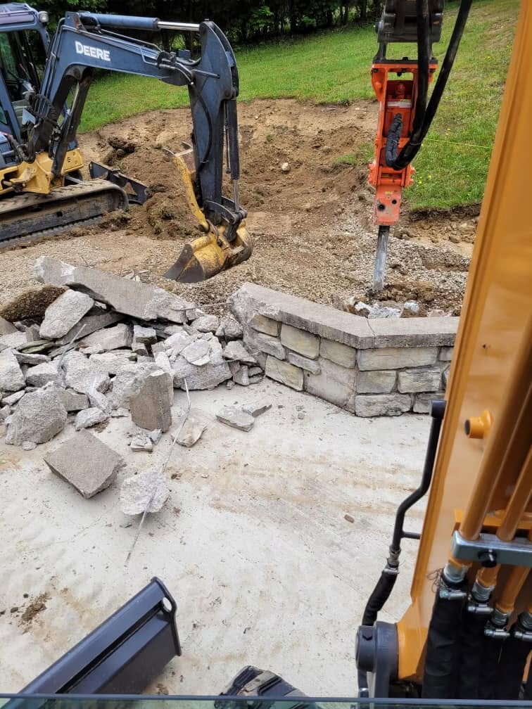 Excavator breaking out concrete during site work